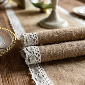 Natural jute table runner with delicate white lace trim on a rustic wooden table surface