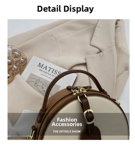 Detail of round two-tone crossbody bag with cream and brown leather and gold hardware