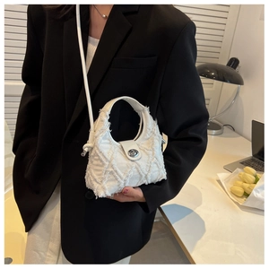 Detailed close-up of a white quilted canvas crossbody bag with silver buckle and frayed edges