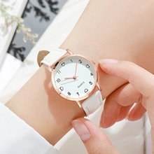 Close-up of white quartz watch with rose gold case and white leather strap on wrist