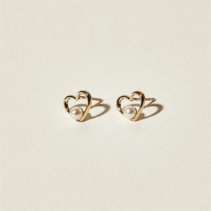 Elegant 925 sterling silver heart-shaped gold studs with white pearls on a cream background