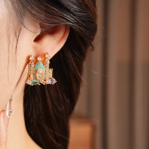 Close-up of gold plated castle stud earring with colorful cubic zirconia on ear