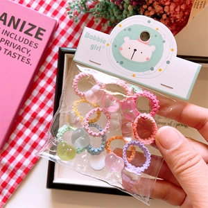 Close-up of macaron-colored knit hair ties with translucent heart beads in hands