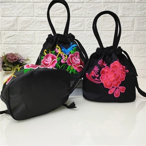 Detailed view of traditional Chinese floral embroidery and drawstring closure on black bag