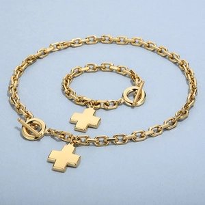 Flat lay of 18K gold plated stainless steel cross necklace and bracelet set with OT toggle