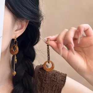 Gros plan détaillé de boucles d'oreilles bohèmes avec anneaux en résine et chaînettes