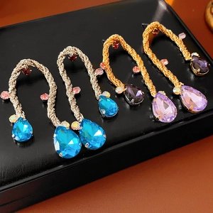 Macro shot of vintage metal braided earrings with teardrop crystals in assorted colors