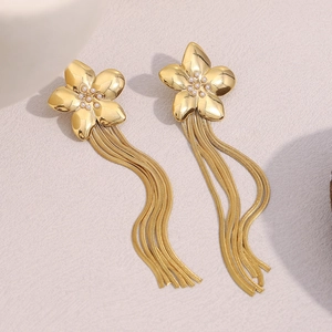 Detailed view of gold flower earrings with pearl accents and long metal tassels