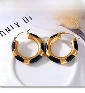 Macro view of gold hoop earrings with black enamel detail and PVD plating finish