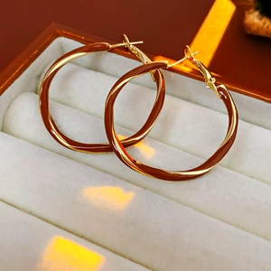Detailed macro view of twisted gold hoop earrings with glossy brown enamel finish