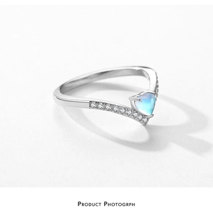 Macro view of a heart-shaped moonstone ring with a V-shaped silver band and micro-pavé stones