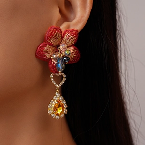 Détail de la boucle d'oreille fleur en tissu rouge vintage avec gouttes de diamant