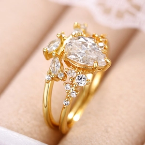 Macro shot of a gold pear-cut zircon ring set with pavé side stones on beige velvet
