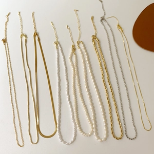 Flat lay of multiple layered necklaces with freshwater pearls and gold snake bone chains