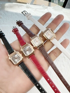 Detailed display of four vintage square ladies' watches in black, red, brown, and white leather