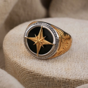 Macro detail of men's S925 ring with golden star and black center on textured fabric