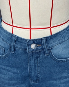 Détail du bouton métallique et couture de la taille sur un jean large délavé bleu