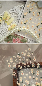 Macro detail of 5D embossed nail stickers featuring yellow flowers and white bows