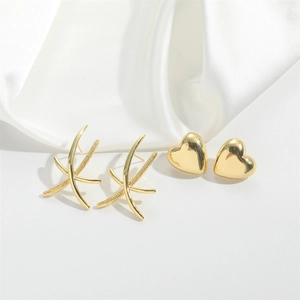 Minimalist gold heart and textured cross earrings set presented on white silk background