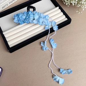 Detail of blue fabric flower hair clip with elegant pearl tassel on black velvet stand