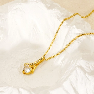 Macro shot of gold-plated necklace featuring a round sparkling zircon pendant on stone