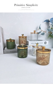 Close-up of luxury striped glass storage jars with gold lids in green and amber