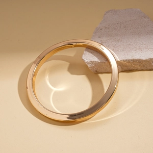 Minimalistischer goldener Metallarmreif auf Naturstein mit glattem Hochglanz-Finish