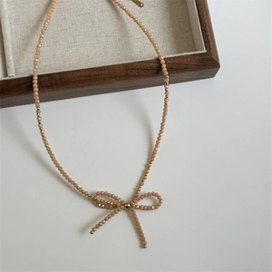 Macro shot of handmade champagne beaded necklace with bow pendant and gold accents