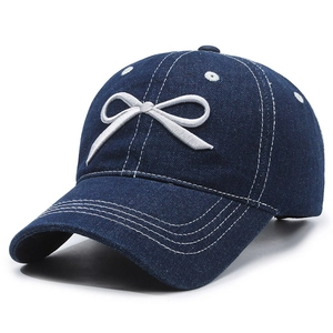 Navy blue denim baseball cap featuring white embroidered bow and vintage washed texture