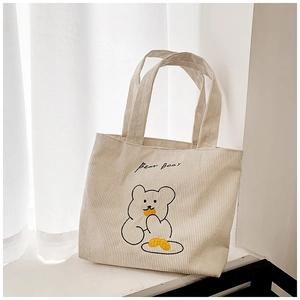 Close-up of beige corduroy fabric texture and cute embroidered cartoon bear on tote bag
