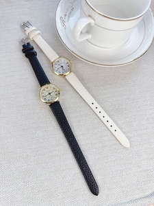 Close-up of black and white leather quartz watches with Roman numeral dial on fabric