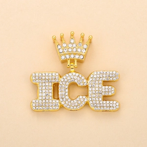 Close-up of golden crown ICE pendant with sparkling clear rhinestones on beige background