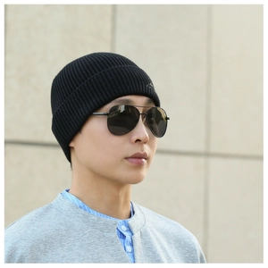 Detailed side view of a black ribbed knit beanie worn by a model in outdoor setting