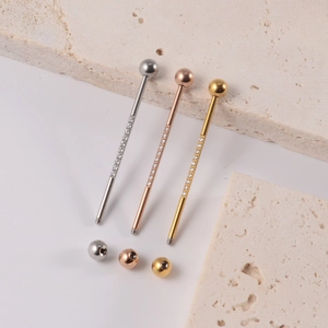 Macro shot of 14G industrial barbell piercings in silver, rose gold and gold with zircon