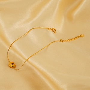 Gold stainless steel bracelet with 18K gold letter C pendant on champagne silk fabric