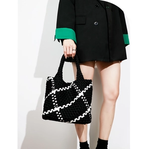 Fashionable black and white woven tote bag shown on a model with a minimalist background