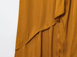 Detail of mustard yellow satin midi dress showing asymmetrical layered fabric texture