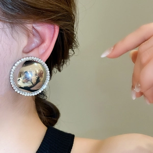 Macro detail of oversized silver circular stud earring with crystal border on model