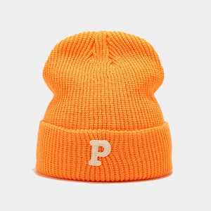 Detailed view of orange ribbed knit beanie with white embroidered P letter patch