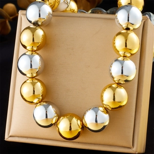 Collier punk avec de grosses boules métalliques dorées et argentées sur support beige