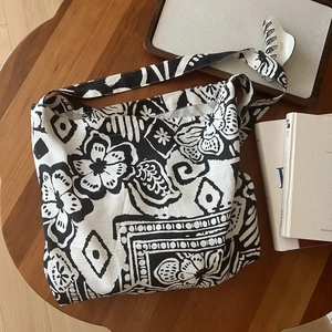 Detail of bohemian black and white floral pattern canvas tote bag on wooden table