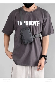Close-up of dark grey waterproof sling bag with woven zipper pullers and nylon strap