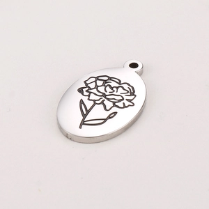 Gros plan d'un pendentif ovale en acier argenté avec une fleur d'œillet gravée