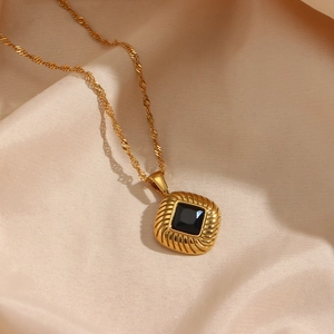 Detailed close-up of a vintage gold rhombus pendant with black zircon on champagne silk