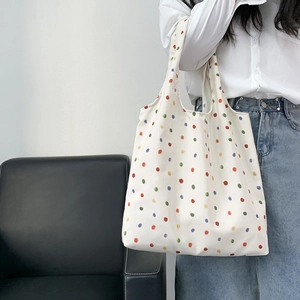 Off-white canvas tote bag with colorful polka dots pattern shown on model's arm
