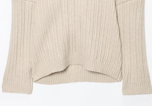 Close-up of ribbed knit texture on light beige sweater hem and cuffs for women
