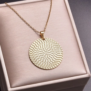Close-up of 18k gold plated round pendant with woven texture in a beige jewelry box