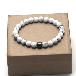 Detail of white howlite beaded bracelet with black cylindrical bead on a jewelry box