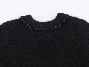 Detail of the black knit sweater with intricate beadwork and plush mohair texture
