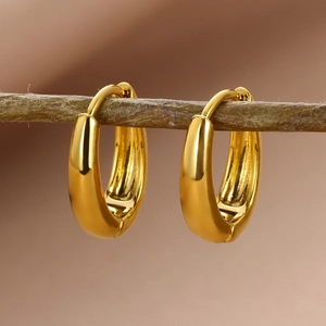 Macro view of gold teardrop hoop earrings hanging on branch with warm bokeh background